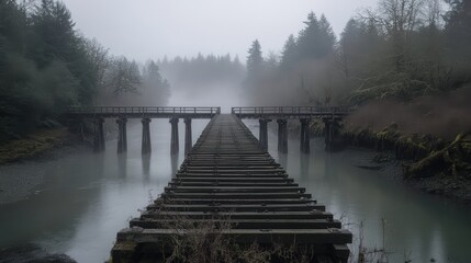 Fototapeta premium Abandoned wooden bridge over foggy river in serene forest landscape capturing tranquil atmosphere