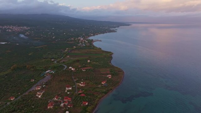 Aerial view of beautiful sunset over the Ionian Sea with serene coastline and picturesque village, Nea Koroni, Greece.