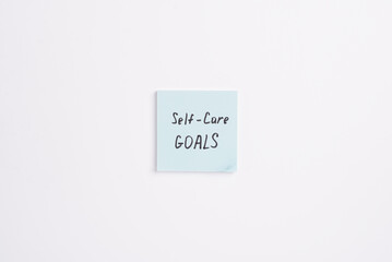 Paper note with words 2025 Self Care Goals on a white minimal background. Concept of goals and...