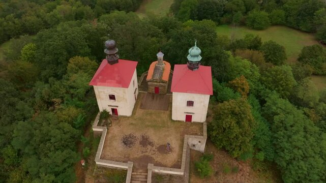 Aerial view of Calvary Ostre church surrounded by beautiful autumn woods and serene countryside, Ustek, Czech Republic.