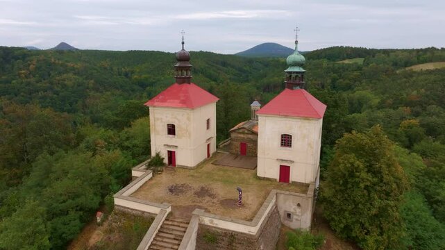 Aerial view of calvary ostre church surrounded by scenic forest and hills, Ustek, Czech Republic.