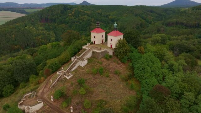 Aerial view of Calvary Ostre church on a scenic hill surrounded by tranquil forest and greenery, Ostre, Czech Republic.
