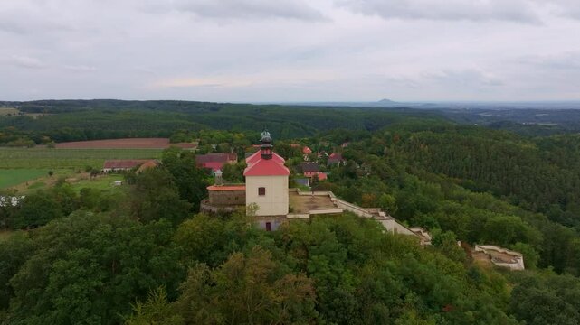 Aerial view of calvary ostre church surrounded by lush greenery and tranquil village, Ustek, Czech Republic.