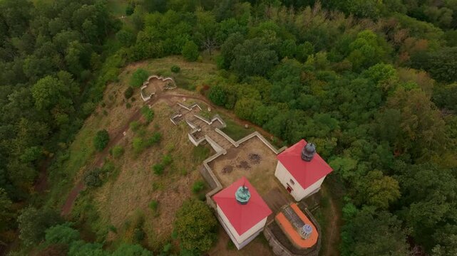 Aerial view of Calvary Ostre church surrounded by lush greenery and tranquil forest on a scenic hill, Ustek, Czech Republic.