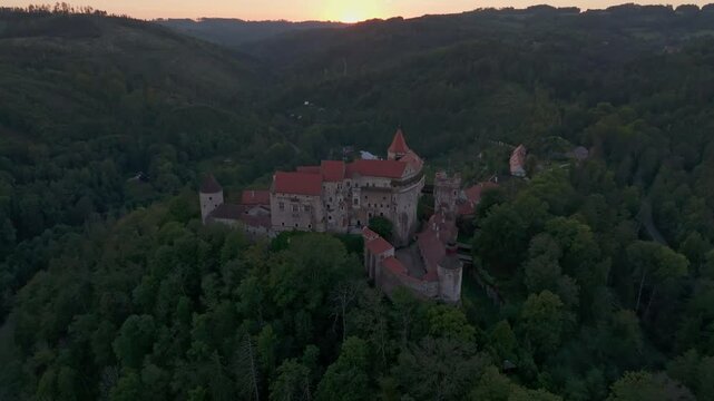 Aerial view of pernstejn castle at sunset surrounded by scenic hills and forest, nedvedice, czech republic.