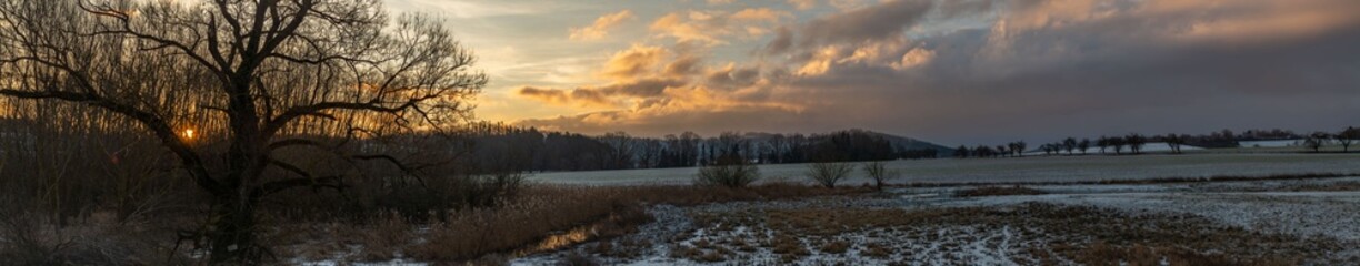 Sunrise with orange sun and winter snowy landscape near Nepomuk town