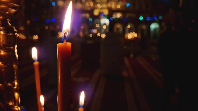 Closeup of a lit candle on the candlestick inside a Christian Orthodox church. The burning flame is sharp and bright. Religious symbol for Easter or Christmas holidays. Religion and creed concept