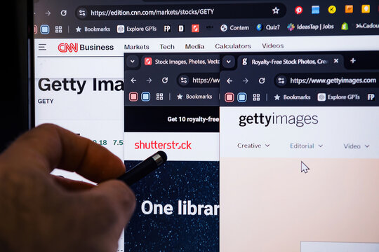 Paris, France - Jan 7, 2025: A hand pointing at a computer screen displaying open tabs for Shutterstock and Getty Images, highlighting stock details and creative content platforms.