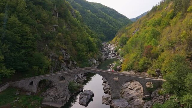 Aerial view of devil's bridge over the arda river surrounded by autumn foliage and mountains, Dyadovtsi, Bulgaria.
