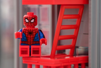 Naklejka premium Tambov, Russian Federation - January 06, 2025 Lego Spiderman minifigure sitting on the fire escape stairs of a house