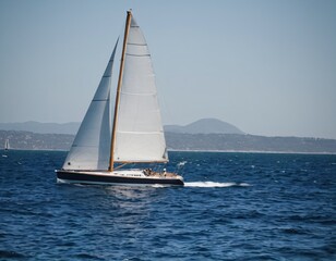 Fototapeta premium Sailing on the Horizon: A sleek sailboat gracefully navigates the open sea under a clear sky, capturing the essence of freedom and adventure. Ai generated image