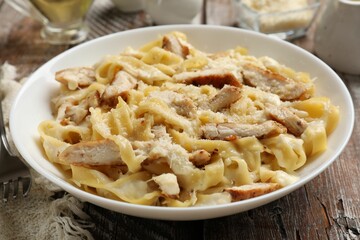 Tasty Alfredo pasta with chicken on wooden table, closeup