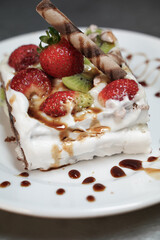 A slice of strawberry avocado cake portioned on a plate, decorated with chocolate and white cream, homemade cake, close up