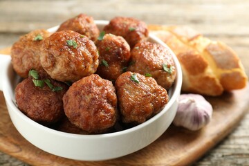Tasty meatballs with green onion in baking dish on wooden table, closeup