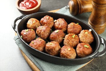 Tasty meatballs in baking dish served on grey table