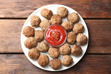 Delicious meatballs with ketchup and spices on wooden table, top view