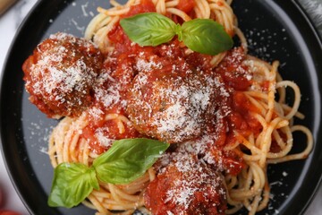 Delicious pasta with meatballs, basil, cheese and tomatoes on table, top view