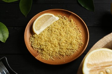 Lemon zest with fresh fruit slice on black wooden table, closeup