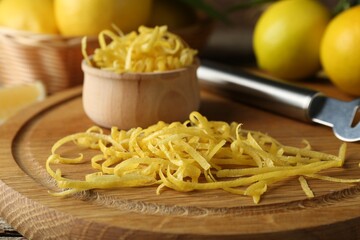 Lemon zest, zester tool and fresh fruits on wooden table, closeup