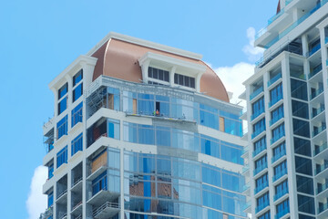 Workers on suspended safety platform repairing modern high-rise building with glass facade.