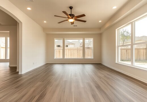 A large open living room with a wooden floor and a ceiling fan