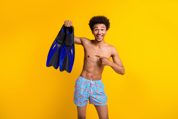 Young man enjoying summer vacation with snorkeling gear against vibrant yellow background, showcasing leisure lifestyle and travel vibes. © deagreez