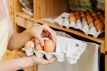 Woman with egg carton box buying bio organic eggs from local farm in zero waste shop.