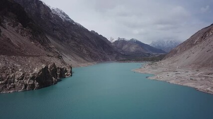 Aerial view of serene Attabad Lake surrounded by majestic mountains and rugged valley, Gojal region, Pakistan.