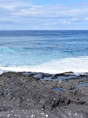 White waves blue ocean and lava rocks on canary coast