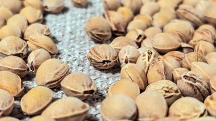 Cherry kernels scattered on textured fabric in a close-up view. Oval shapes with visible cracks and grooves. Earthy tones emphasize the natural texture and raw appearance of the kernels
