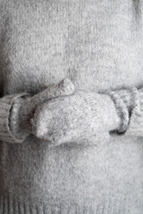 Frozen. Young woman in warm sweater and mittens shivering from cold. Mittens, gloves close-up