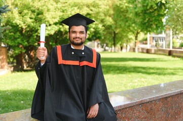 Handsome indian graduate in graduation glow with diploma