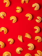 Golden fortune cookies scattered on a bright red background. 