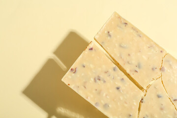 Pieces of tasty white chocolate on beige background, top view. Space for text