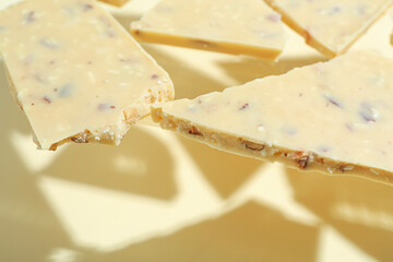 Pieces of tasty white chocolate on beige background, closeup