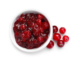 Tasty cranberry sauce in bowl and berries isolated on white, top view