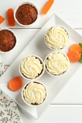Tasty carrot muffins with fresh vegetables on white wooden table, flat lay