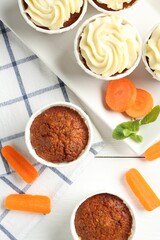 Delicious carrot muffins with fresh vegetables and mint on white wooden table, flat lay