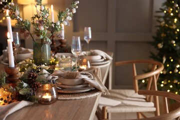 Christmas celebration. Festive table setting with dishware, glasses and decor in room