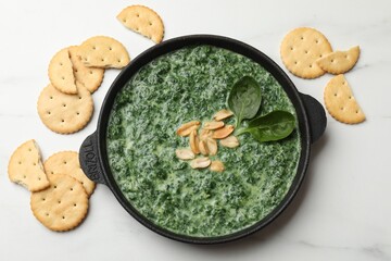Delicious spinach sauce with peanuts and crackers on white table, flat lay