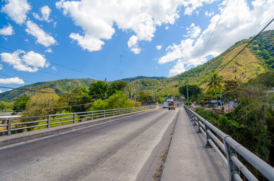 Panoramic view of a bridge over the CA1 Guatemala highway, surrounded by vegetation and green mountains.