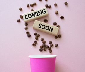 Coming Soon symbol. Concept word Coming Soon on wooden blocks. Beautiful pink background with coffee cup. Business and Coming Soon concept. Copy space