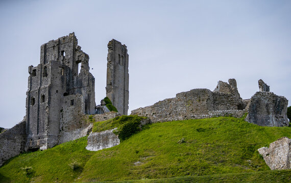 View of historic Corfe Castle ruins on a green hill in the Purbeck Hills, Wareham, United Kingdom.