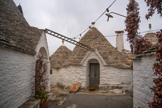 View of charming trulli stone houses with picturesque roofs and chimneys, Alberobello, Italy.