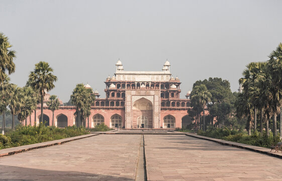 Agra, India - 01 December 2024: View of the Tomb of Akbar with red sandstone architecture and palm trees, Agra, India.