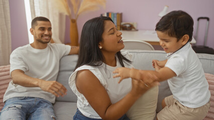 Fototapeta premium Latin family spending quality time together in a cozy living room, with a woman holding a child and a man sitting on the couch