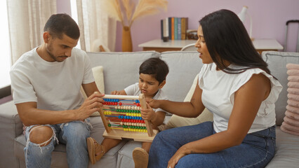 Obraz premium Family enjoying time together in a living room, with a man and woman helping a child play with an abacus on the couch, creating a warm and loving indoor environment.