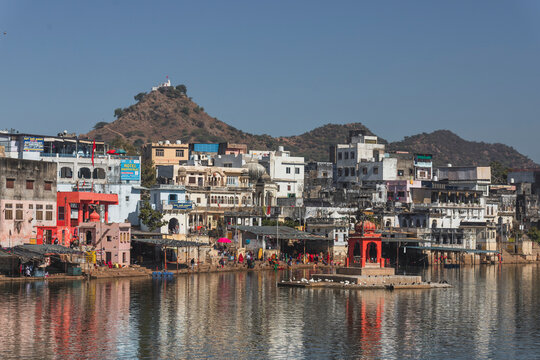 Pushkar, India - 14 December 2024: View of colorful buildings and a serene lake with reflections, Pushkar, Rajasthan, India.