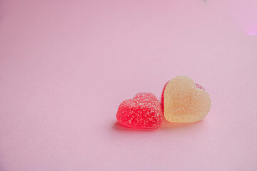 Fototapeta premium Multicolored gummy hearts on pink background side view for Valentine's Day