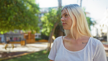 Young woman with blonde hair standing in an outdoor urban park on a sunny day